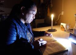 Ciudadana alumbra con velas y linternas para leer un libro.