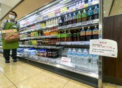 Un miembro del personal trabaja con botellas de agua con un cartel escrito el agua embotellada está racionada, con una tapa de una caja (seis botellas) por cada cliente en un supermercado en el distrito Sumida de Tokio en agosto.