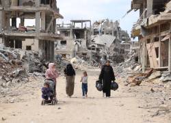 Mujeres y niños palestinos caminan por un camino de tierra bordeado de escombros de construcción en el barrio de Shujaiya de la ciudad de Gaza el 7 de octubre de 2024.