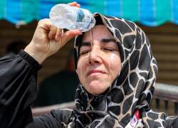 Una peregrina musulmana turca que sale se vierte agua fría de una botella en la cabeza para refrescarse mientras espera en la ciudad santa de La Meca, en Arabia Saudita, el 20 de junio de 2024.