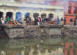 Imagen que muestra piras fúnebres al pie de un río en India.