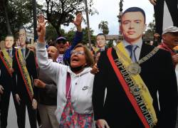 Una simpatizante del presidente de Ecuador, Daniel Noboa, gritan consignas junto a figuras con la imagen de Noboa este domingo, afuera del Palacio de Gobierno en Quito.