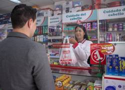 Colaboradora atiende a un cliente en una farmacia.