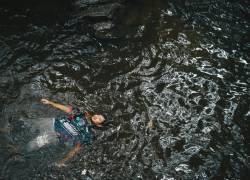 Fotografía referencial de un joven nadando en un estanque.