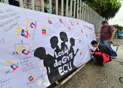 Los manifestantes escriben en una pancarta durante una manifestación contra la desaparición de cuatro menores que desaparecieron durante una operación militar, frente al juzgado de Guayaquil, Ecuador, el 31 de diciembre de 2024.