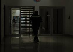 Fotografía de un trabajador caminando al interior de un edificio a oscuras.