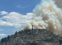 Fotografía en la que se observa el manto de humo que se formó detrás de la escultura a la virgen de El Panecillo, un monumento histórico de Quito.