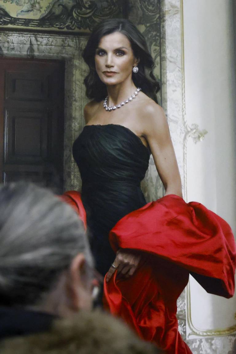 $!Foto donde se ve a una persona viendo de cerca el nuevo retrato oficial de la reina Letizia, en el que lleva un vestido negro con capa fucsia de Balenciaga.