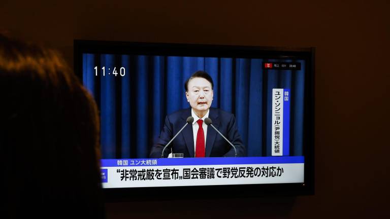 Un turista surcoreano mira una transmisión de televisión japonesa que muestra al presidente surcoreano, Yoon Suk Yeol, declarando la ley marcial en un discurso de emergencia televisado pronunciado desde la oficina presidencial en Seúl.