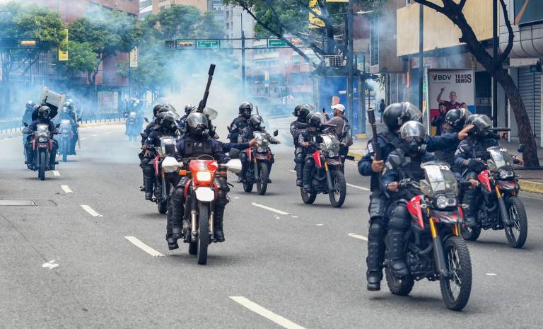 $!Miembros del escuadrón antidisturbios de la Guardia Nacional se alejan de los gases lacrimógenos en el barrio de Chacao mientras opositores del presidente venezolano, Nicolás Maduro, participan en una manifestación, en Caracas, el 30 de julio de 2024.