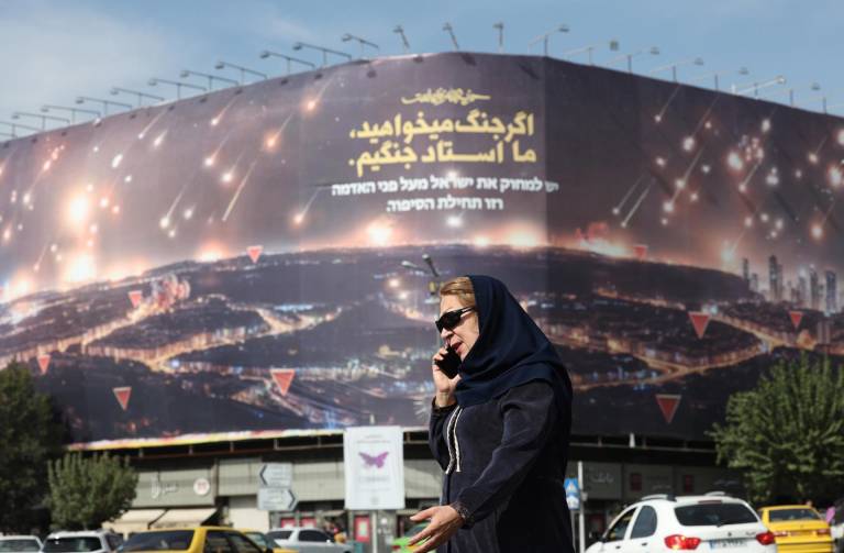 $!Tehran (Irán), 26/10/2024.- Una mujer camina cerca de un cartel anti-Israel que muestra el reciente ataque de ese país. El anuncio dice: Si quieres guerra, somos el maestro de la guerra.