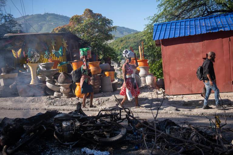 $!Personas pasan frente a los restos de una hoguera donde incineraron a un pandillero este martes, en una calle de Puerto Príncipe (Haití).