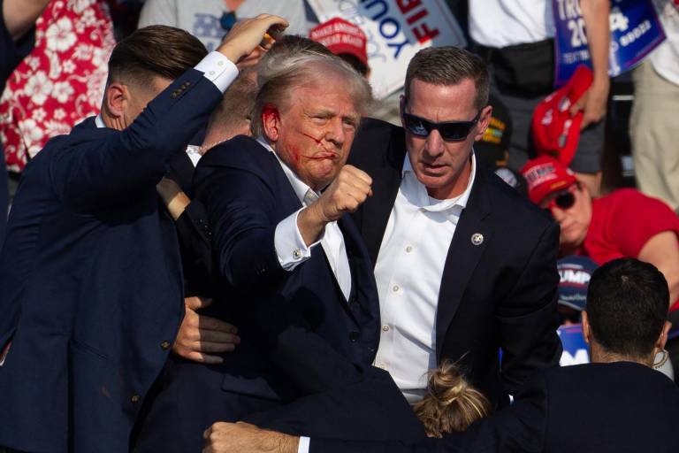 $!Se ve al candidato republicano estadounidense Donald Trump con sangre en el rostro rodeado de agentes del servicio secreto cuando lo sacan del escenario en un evento de campaña en Butler Farm Show Inc. en Butler, Pensilvania, el 13 de julio de 2024.