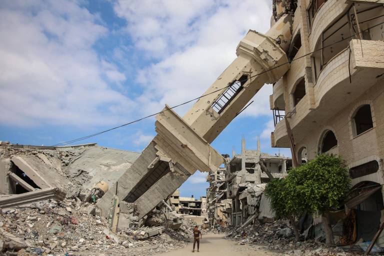 $!Palestinos caminan bajo el minarete inclinado de una mezquita destruida en el barrio de Shujaiya de la ciudad de Gaza el 7 de octubre de 2024.