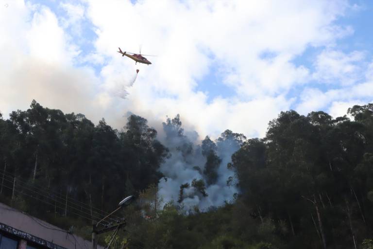 $!Un helicóptero lanzando agua a uno de los focos del incendio en las laderas de El Panecillo.