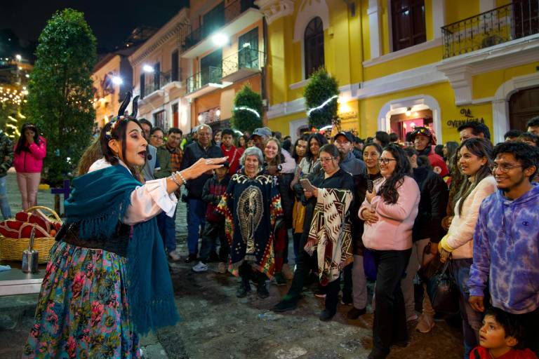 $!Una mujer disfrazada habla con personas en una calle el pasado jueves en Quito.