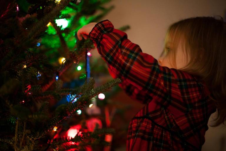 $!Niña decorando árbol de Navidad en casa.