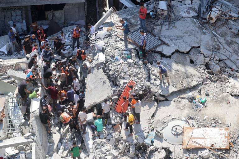 $!Palestinos buscan supervivientes entre los escombros de un edificio, que se derrumbó tras el bombardeo israelí sobre un edificio contiguo, en el barrio de Sheikh Radwan en la ciudad de Gaza