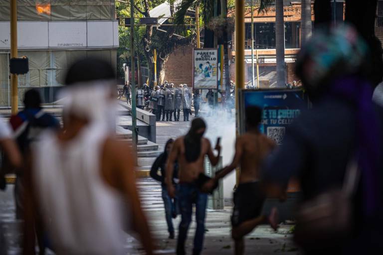 $!Manifestantes corren durante enfrentamientos entre opositores y miembros de la Guardia Nacional Bolivariana (GNB), por los resultados de las elecciones presidenciales este lunes, en Caracas.