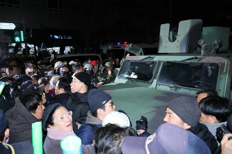 $!La gente rodea un vehículo militar frente a la Asamblea Nacional en Seúl después de que el presidente surcoreano, Yoon Suk Yeol, declarara la ley marcial.