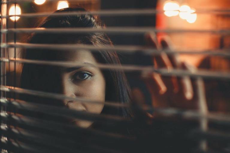 $!Fotografía referencial de una mujer espiando desde atrás de sus cortinas.