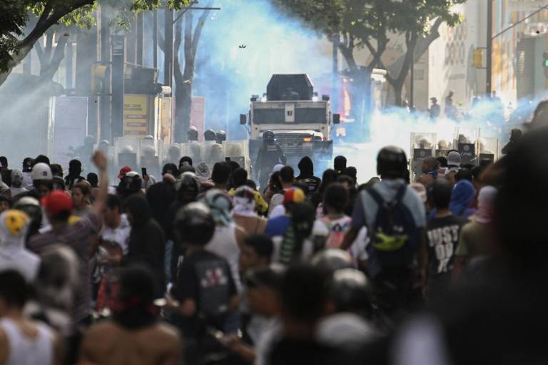 $!Los manifestantes chocan con la policía cerca de un vehículo policial blindado durante una protesta contra el presidente venezolano, Nicolás Maduro, en Caracas el 29 de julio de 2024, un día después de las elecciones presidenciales venezolanas.