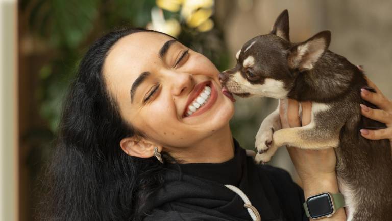 Una chica junto a su perrito recibiendo una dosis de amor.