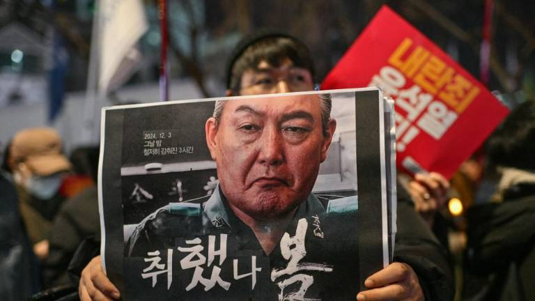 Manifestante sostiene un cartel con la imagen del presidente Yoon Suk-yeol durante una manifestación con velas en Seúl pidiendo su destitución.