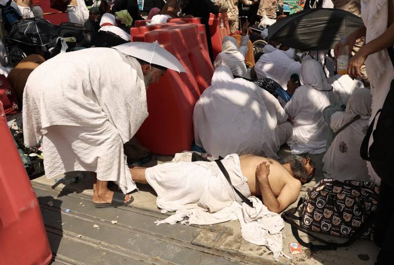 $!Un hombre yace en el suelo afectado por el calor abrasador, mientras es ayudado por otro peregrino musulmán en el lugar del ritual simbólico de la lapidación del diablo durante la peregrinación anual hajj en Mina el 16 de junio de 2024.