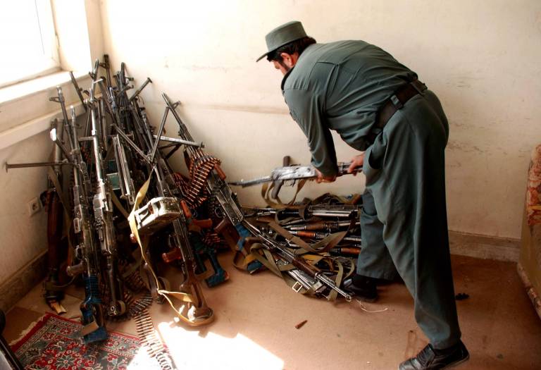 $!Esta fotografía tomada el 2 de octubre de 2010 muestra a un policía afgano inspeccionando armas recogidas en una empresa de seguridad privada en Herat.