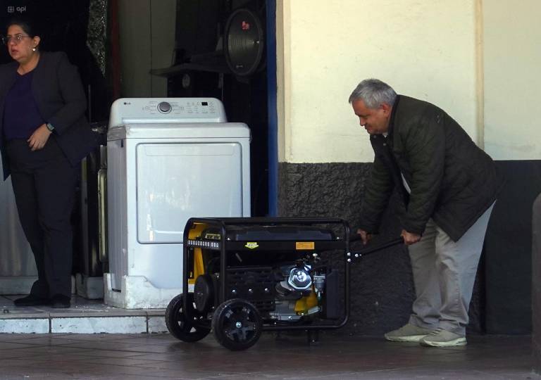 $!Un trabajador enciende un generador de electricidad a las afueras de un local en Cuenca.