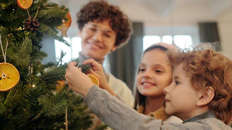 Niños participando en la decoración del árbol de Navidad familiar.