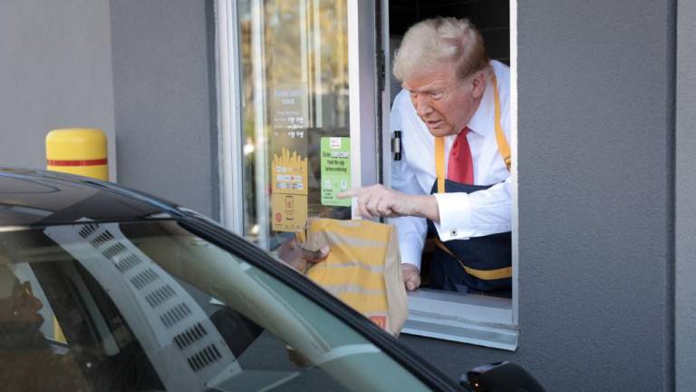 El candidato presidencial republicano y ex presidente de EE. UU., Donald Trump, atendiendo la fila del servicio de autos.